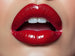 Picture of a womens ruby red lips and her tounge and teeth are showing.